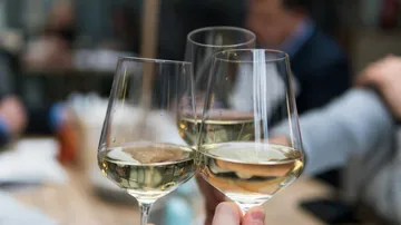 Gläser mit Weißwein stoßen an, um zu feiern.