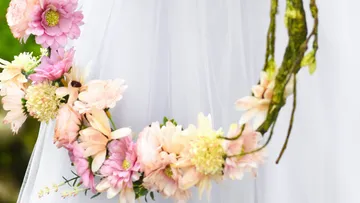 Blumenkranz hängt dekorativ an einem weißen Stoff.