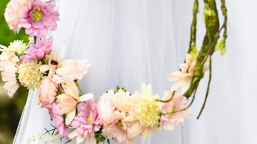 Blumenkranz hängt an einem weißen, schimmernden Kleid.