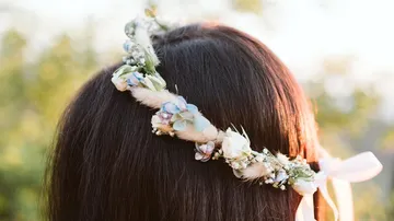 Wreath of flowers adorns a person's hair in nature.