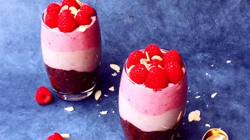 Two glass desserts decorated with raspberries and almonds.