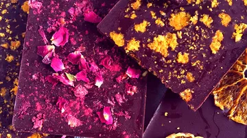 Dunkle Schokolade mit bunten Blumen und Fruchtstücken dekoriert.