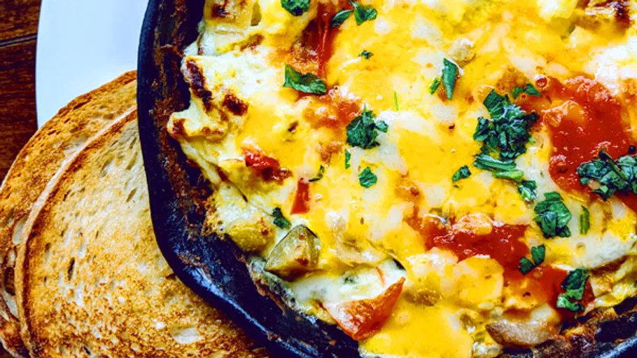 Iron pan with melted cheese and toasted bread.