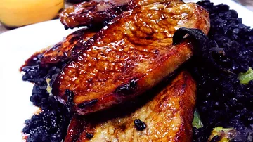 Juicy piece of meat lies on black rice.