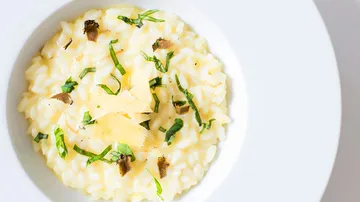 Creamy risotto with herbs and truffles on a white plate.
