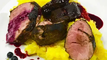 Zarte Fleischstücke mit püriertem Gemüse auf weißem Teller.