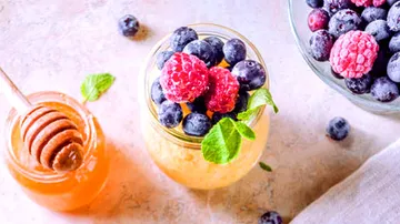 Glass with fruit, honey next to it; fresh, bright environment.
