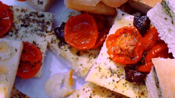 Gebäck mit getrockneten Tomaten und Oliven auf einem Tisch.