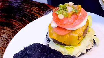 Ein Burger mit bunten Zutaten auf einem weißen Teller.