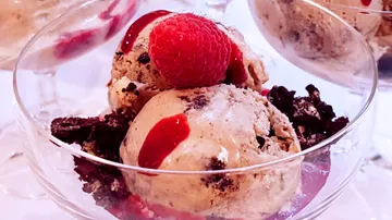 Eiscreme mit Himbeeren und Schokoladenstückchen in Schalen.