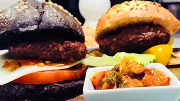 Schwarze und helle Hamburger mit Beilagen auf einem Teller.