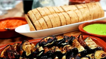 Gegrilltes Gemüse, serviert mit Brot und Saucen auf Tisch.