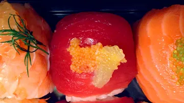 Bunte Sushi-Stücke liegen auf einem dunklen Untergrund.
