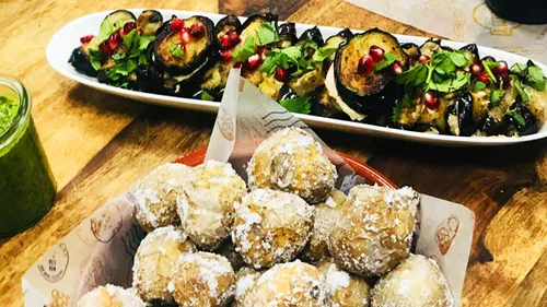 Frittierte Snacks liegen auf einem Holztisch neben Gemüse.