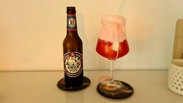 Bottle of beer and glass with frothy drink on table.