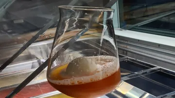 A glass of frothy drink is on a shelf.