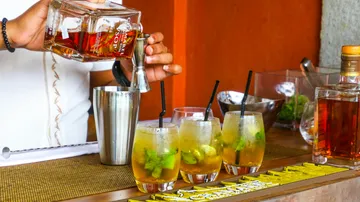 Bartender pours spirits into glasses at a bar.