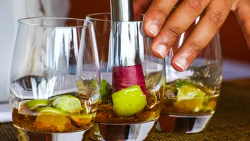 Glasses with limes and drink are mixed with a pestle.