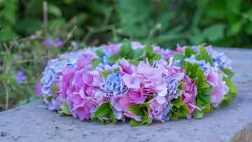 A wreath of flowers is lying on an outdoor grey stone.