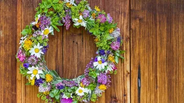 Blumenkranz hängt an rustikaler Holzwand.