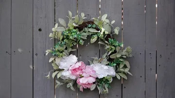 A blooming wreath hangs on a grey wall.
