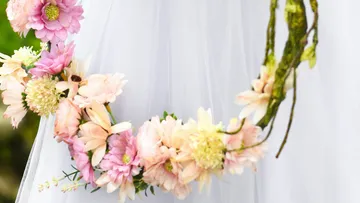 Blumenkranz hängt sanft an einem weißen Kleid.
