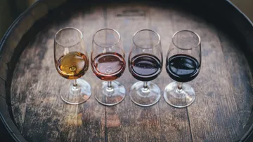 Four wine glasses stand on a wooden barrel.