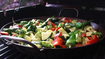 Pan-fry vegetables on grill, colorful ingredients visible.
