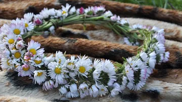 Ein Blumenkranz liegt auf einem weichen, gemusterten Untergrund.