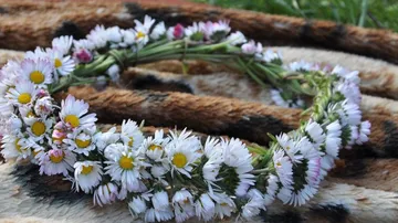 Wreath of flowers is lying on a patterned fabric outdoors.