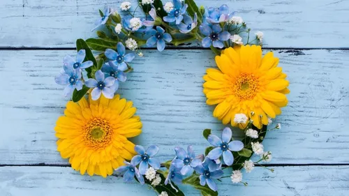 A wreath of colorful flowers on blue wood.