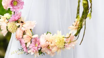 Blumenkranz hängt an einem weißen Kleid im Freien.