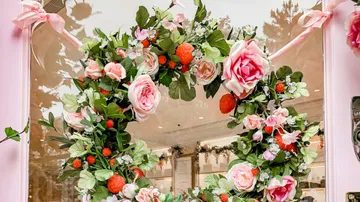 A flower wreath decorates an entrance with pink and green elements.