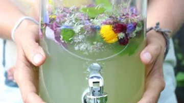 Glasbehälter mit bunten Blumen hält erfrischendes Getränk.