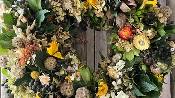 Wreath of dried flowers hangs on a wooden surface.
