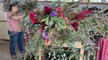 Flower arrangement is arranged by a woman in workshop.
