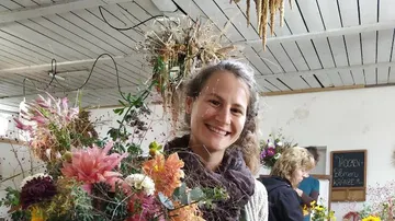 Frau lächelt, während sie einen Blumenstrauß hält.
