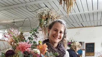 Frau lächelt, während sie einen Blumenstrauß hält, in einem Raum.