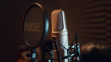 Microphone stands in front of a black screen protector in the studio.