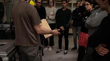 A teacher shows a piece of wood to a group.