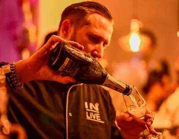 Ein Barkeeper schenkt Sekt in ein Glas in einer Bar.