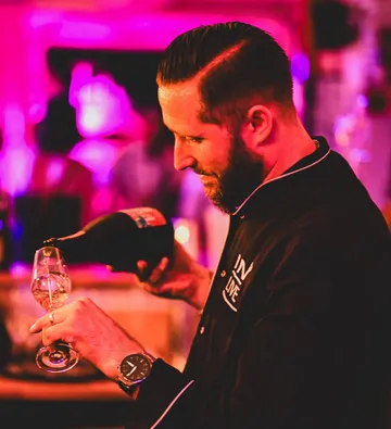 Ein Barkeeper schenkt Sekt in ein Glas in einer Bar.