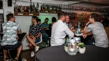 People are sitting in a bar smiling and talking.