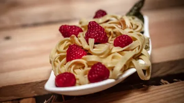 Pasta mit Himbeeren in einer Schüssel auf einem Tisch.