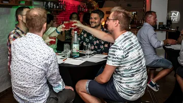 Vier Personen stoßen mit Getränken in einer Bar an.