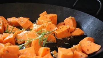 Fry cooked sweet potato cubes in a pan.