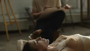 A person lies relaxed while someone draws.
