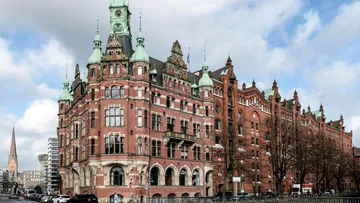 Historic building stands in a city with clouds.