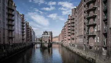 Brick buildings along a quiet canal under blue skies.