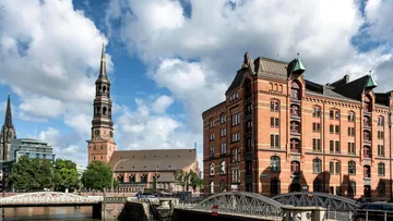 Rotes Gebäude und Kirchturm vor blauem Himmel.